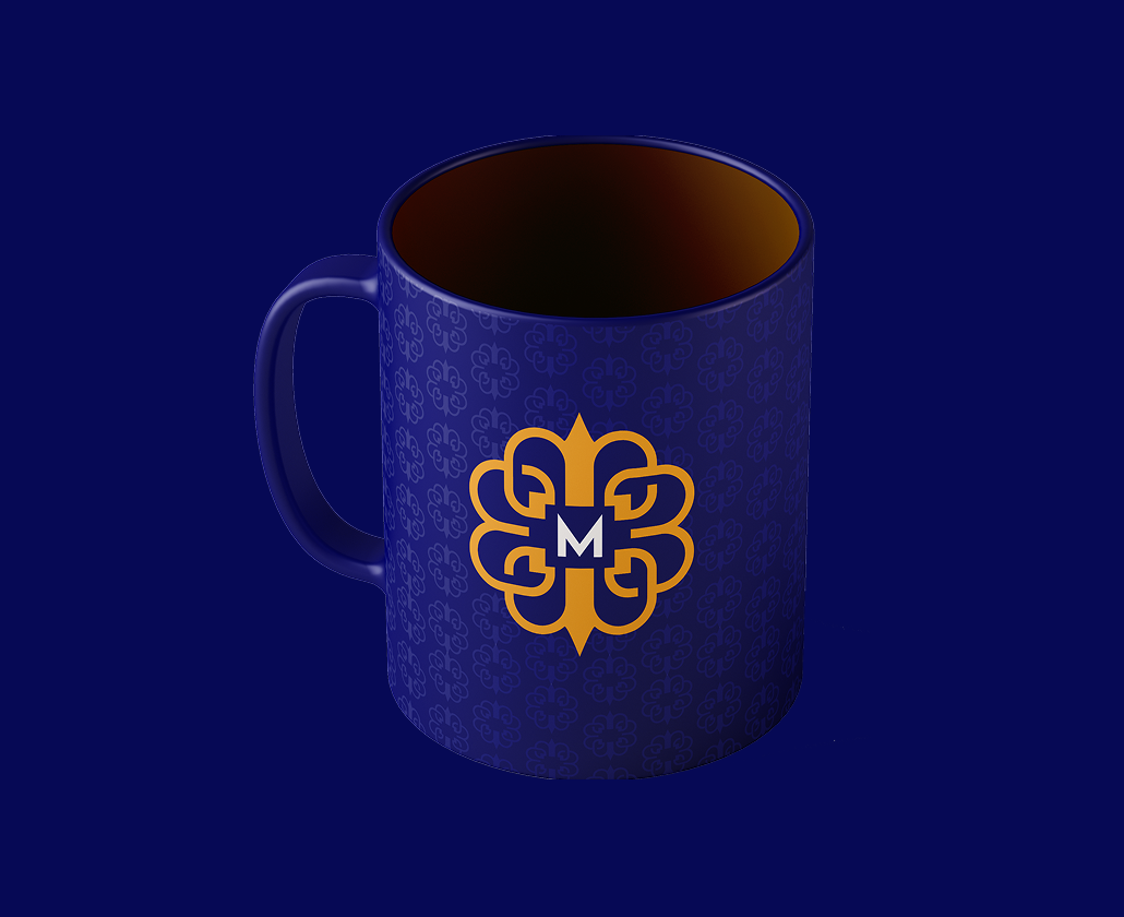 Blue Mercantile mug with the gold monogram and repeating pattern.